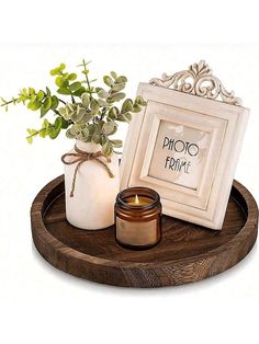 a wooden tray with a candle, vase and picture frame sitting on top of it