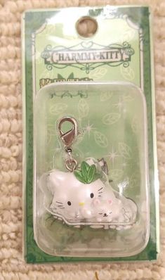 a hello kitty keychain with a green leaf on it