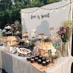 a table topped with cakes and desserts under a white sign that says love is sweet