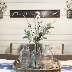 two vases with flowers are sitting on a tray in front of a sign that reads,