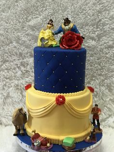 a three tiered cake with beauty and the beast figurines sitting on top