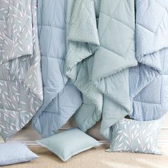 blue and white bedding with polka dot pillows on the floor next to each other