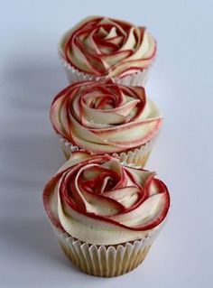 three cupcakes with red and white frosting on them sitting side by side