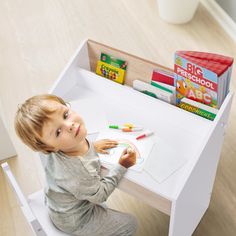 a little boy sitting at a table with some crayons