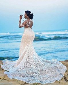 a woman standing on top of a beach next to the ocean wearing a white dress