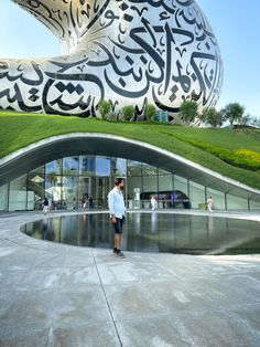 a man standing in front of a building with an artistic design on it's side