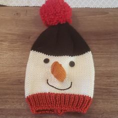 a knitted snowman hat with a red pom - pom