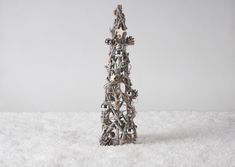 a silver christmas tree made out of metal balls and bells on top of snow covered ground