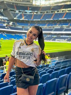 a beautiful woman standing in front of a soccer goalie's uniform at a stadium