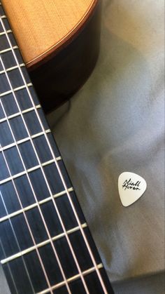 a guitar pick sitting on top of a gray cloth next to a wooden necktie