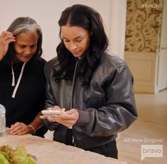 two women standing at a table looking at their cell phones