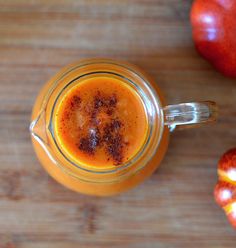 an apple cider is sitting on a wooden table next to two pieces of fruit