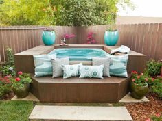 an outdoor hot tub surrounded by flowers and potted plants