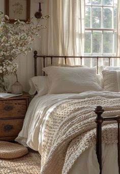 a bed with white linens and pillows in a bedroom next to an open window