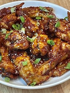 a white plate topped with chicken wings covered in sesame seeds and seasoning on top of a wooden table