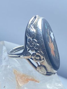 "Floral ring Art Deco floral sterling silver women influenced by Arts and Crafts movement AS IS one stone is missing - Green Leaf Size 5 Weight 6.2g Length 1. 1/8\" Width. 3/4\" Thinnest part 3/32\" Free Shipping & Free Postal Insurance Delivered in a Gift Box If you do not want the ring polished and want to leave the natural patina please let me know at the time of purchase as I do polish rings before I ship rings out. Thanks Free First Class shipping and postal insurance is included. If yo Vintage Silver Turquoise Ring For Wedding, Ornate 925 Stamped Round Rings, Vintage Silver Turquoise Ring For Formal Occasions, Collectible Open Rings, Formal Flower Shaped 925 Silver Ring, Silver Oval Heirloom Flower Ring, Silver Heirloom Flower Ring With Oval Shape, Antique Sterling Silver Rings With Stone Setting, Silver Heirloom Oval Flower Ring