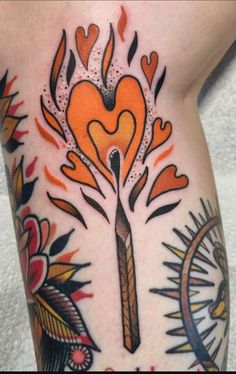 a tattoo with an orange heart and a knife on it's side, surrounded by flames