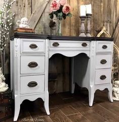 an old white desk with flowers on top and candles in vases next to it