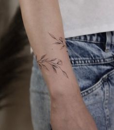 a woman's arm with a small flower tattoo on the left side of her arm