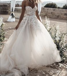 a woman in a wedding dress is standing outside