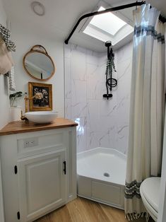 a bathroom with a sink, toilet and bathtub next to a shower curtain that has a skylight above it