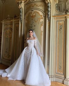 a woman in a wedding dress standing next to a wall with gold and white decorations