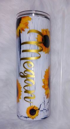 a white and yellow tumbler with sunflowers painted on it's side