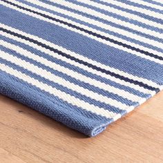 a blue and white striped rug sitting on top of a wooden floor