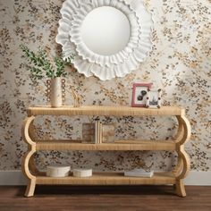 a wooden shelf with vases on it and a round mirror above the top, against a floral wallpapered wall