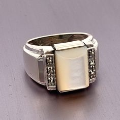 "Rectangle White Mother of Pearl and Marcasite Sterling Silver Vintage Ring ET504 Ring Size: 6.25: can be sized Metal Content: .925 Sterling Silver Face Height (North to South): 1/2\" (13mm) Face Width (East to West): 19/16\" (15m) Height of ring off of finger: 7mm Width of shank: tapers to 5 mm Gemstone: Mother of Pearl Size: 12mm by 9mm Weight: 7.8 Grams Stamps: .925 Condition: Excellent Vintage Condition Each piece is thoroughly examined and refinished as needed by our professional jewelers, Formal Rectangular Ring Stamped 925, White Rectangular Jewelry For Anniversary, White Rings With Rectangular Stone For Formal Occasions, Formal White Rectangular Ring, Classic White Rectangular Ring, Vintage White Rectangular Rings, Rectangular White Gemstone Rings, Rectangular White Jewelry With Polished Finish, White Rectangular Gemstone Rings