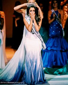 a woman in a blue and white dress is holding her hands up to her face