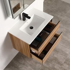 a bathroom sink sitting under a mirror on top of a wooden cabinet next to a white wall