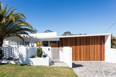 a white house with wooden garage doors and palm trees