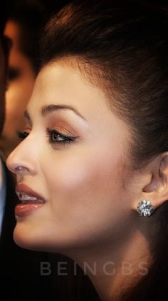 a close up of a woman with earrings on her ear and a man in the background