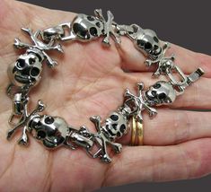 Add a touch of edgy style to your accessory collection with this stunning Steel Skulls Chain Links Bracelet with Black Crystal Eyes.  The bold skull details with striking black crystal eyes bring a unique and fierce element to any outfit. Made with durable steel chain links, this bracelet is perfect for those who love a statement piece that stands out.  Whether you're looking to add a touch of rock 'n' roll to your ensemble or just want to show off your inner rebel, this bracelet is sure to make Goth Bracelets, Skull Accessories, Gothic Bracelet, Crystal Eyes, Crystal Eye, Edgy Style, Chain Links, Halloween Jewelry, Gothic Style