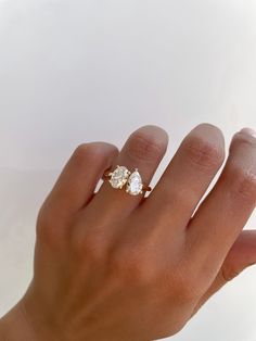 a woman's hand with a diamond ring on top of her finger, against a white background