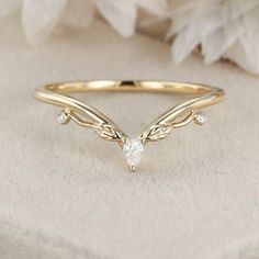 a gold ring with a small white diamond on the top and leaves in the middle