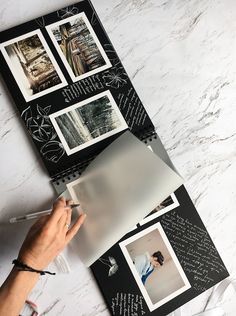 a person is writing on a piece of paper with black and white pictures behind it