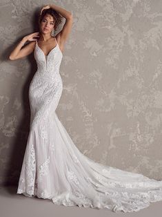 a woman in a wedding dress posing for the camera with her hand on her head