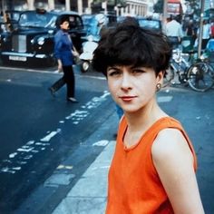 a woman in an orange top standing on the street