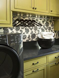 a washer and dryer in a kitchen with green cabinets, black counter tops