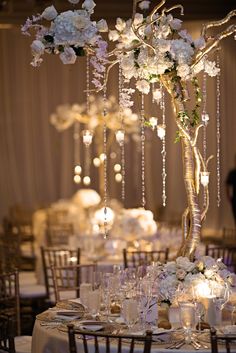 the centerpieces are decorated with white flowers and crystal beaded chandeliers