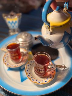 tea being poured into two cups on a blue and white plate