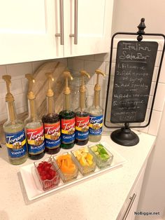 a kitchen counter topped with lots of different types of condiments next to a chalk board