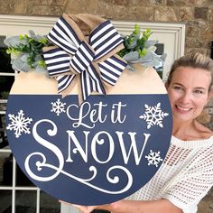 a woman holding up a sign that says let it snow