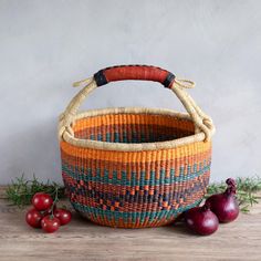 an orange and blue basket sitting on top of a wooden table next to cherries