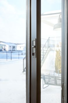 an open door leading to a balcony with snow on the ground and buildings in the background