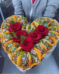 a heart shaped cake with flowers on top is being held by a woman's hands