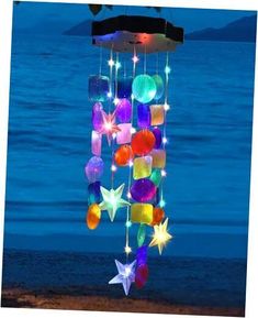 a wind chime hanging from the side of a beach next to the ocean at night