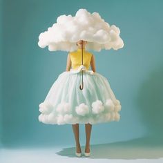 a woman in a yellow shirt and white skirt holding an umbrella over her head while standing under a cloud